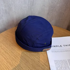 Detail of dark blue nylon docker hat featuring a RIDER patch on a wooden background