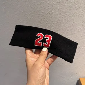 Detail of black athletic headband featuring a red embroidered number 23 with white outline