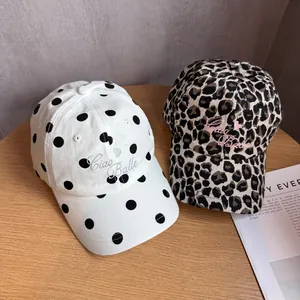 Detail of vintage baseball caps with polka dot and leopard patterns and Ciao Bella embroidery