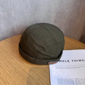 Detail of army green nylon skullcap with RIDER embroidery on light wood surface