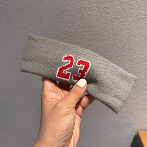 Detailed shot of gray knitted sports headband featuring red number 23 embroidery