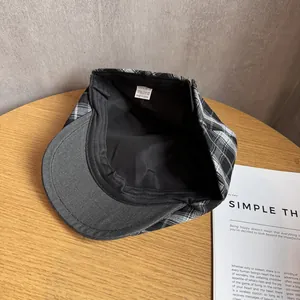 Detail view of the black and white plaid newsboy cap showing inner lining and fabric texture
