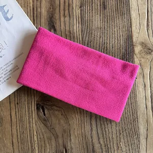 Close-up of rose red knitted headband showing soft fabric texture on a wooden table