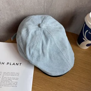 Close-up of light blue denim flat cap with twill texture on a wooden table surface