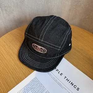 Λεπτομέρεια καπέλου camper από denim με αντιθετικές ραφές και ετικέτα σε ξύλινο φόντο