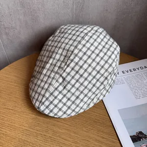 Détail d'une casquette plate à carreaux noir et blanc sur une table en bois avec revue