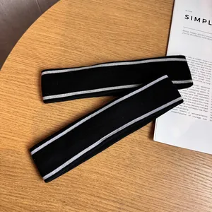 Set of two black knitted athletic headbands with white stripes on a wooden surface