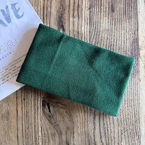Detail of dark green knitted headband texture on a wooden table with casual lifestyle setting