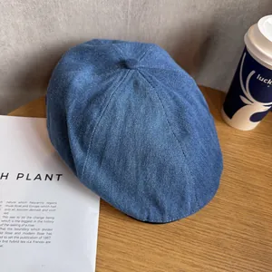 Detailed close-up of dark blue denim beret cap on light wooden texture with soft lighting