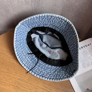 Détail d'un bob en jean bleu avec broderie cœur rose et cordon de serrage réglable interne