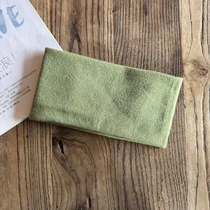 Detail of grass green knitted headband with vertical rib texture on wood surface