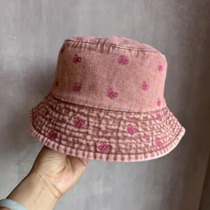 Gros plan du chapeau bob en denim rose avec broderie détaillée de papillon rose