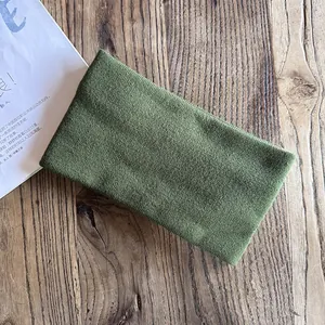 Close-up of dark green knitted headband with vertical texture on a wooden background