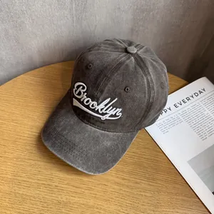 Detail of washed grey baseball cap with white Brooklyn embroidery on a wooden table
