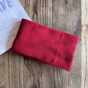 Detail of dark red knitted headband with ribbed texture on a rustic wooden background