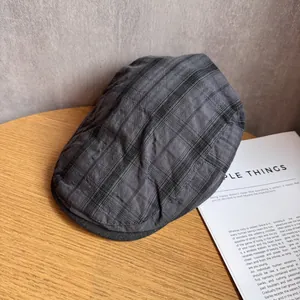 Close-up of dark grey plaid fabric texture on a retro newsboy cap with neat stitching