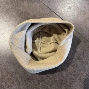 Dettaglio delle robuste cuciture a croce all'interno di un berretto in maglia beige
