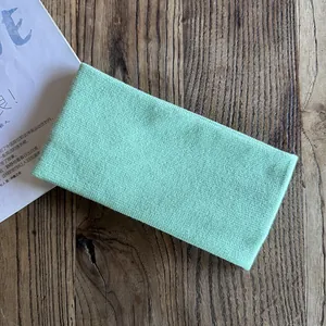 Detailed view of mint green knitted headband texture on rustic dark wood background