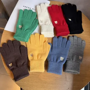 Detailed view of knitted bear embroidery on colorful winter gloves with ribbed cuffs