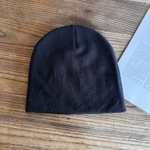 Vista piatta di un berretto nero in maglia su legno scuro con una rivista vintage