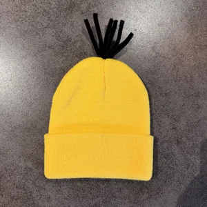 Gelbe Strickmütze im Minion-Stil mit schwarzen Haarsträhnen und Umschlag auf Grau