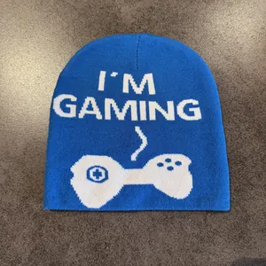 Detail of blue knitted beanie featuring I'M GAMING text and controller jacquard pattern
