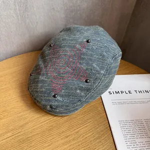 Détails d'une casquette en denim avec broderies rouges et rivets sur table en bois