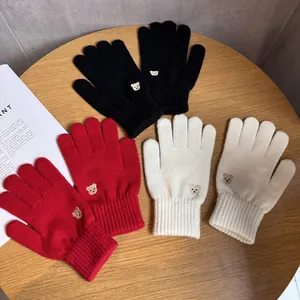 Detailed view of knitted bear embroidery gloves in black, red, and beige wool blend