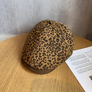 Detailed view of leopard print flat cap with brown suede brim on a wooden surface