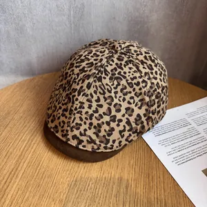 Detailed close-up of leopard print flat cap with a contrasting brown brim on a wooden surface