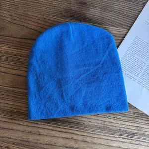 Dettaglio del berretto in maglia blu brillante su legno con libro di lifestyle in posa