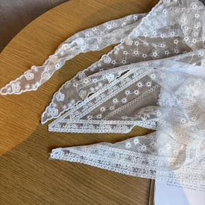 Makroaufnahme von weißem Blumenstickerei-Spitzenband mit Wellenrand auf einem Holztisch