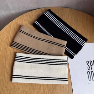 Fasce per capelli in maglia a righe nei colori nero, cammello e beige su legno