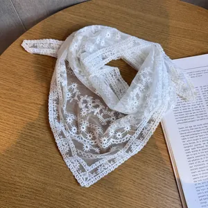 Eleganter weißer Spitzen-Dreiecksschal mit Blumenstickerei auf einem Holztisch