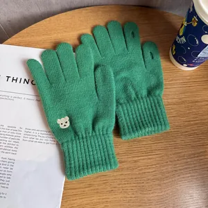 Detail of green knitted gloves with bear embroidery and functional finger openings