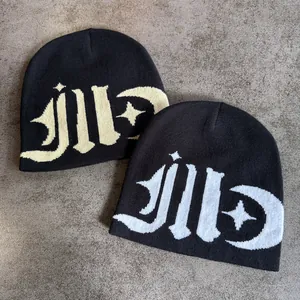 Detail of two black beanies with gothic letter jacquard and star patterns on gray ground