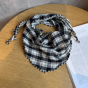 Dettaglio di un foulard a triangolo a quadretti bianchi e neri con bordi ondulati