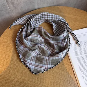 Dettaglio di foulard a quadretti vintage con bordo in pizzo su tavolo in legno