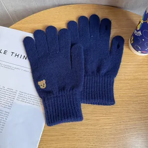 Close-up of navy knit gloves with gold bear embroidery and touch screen finger opening