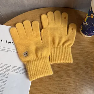 Detail of ginger yellow knit gloves with bear embroidery and touch-screen finger openings