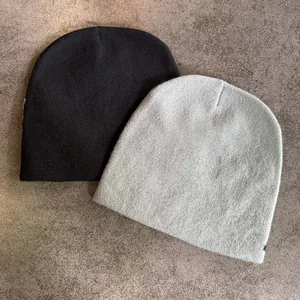 Bonnets en tricot à motif d'étoile en noir et gris clair sur surface en pierre