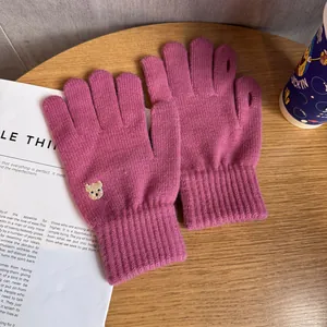 Detailed view of rose red knitted gloves with cute bear embroidery and finger openings