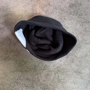 Détail de la maille côtelée et du bloc de couleur géométrique sur un bonnet noir