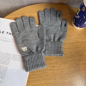 Close-up of gray knitted gloves with bear embroidery and touch screen finger openings