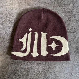 Flat lay of brown beanie with white jacquard moon and star knit patterns on stone background