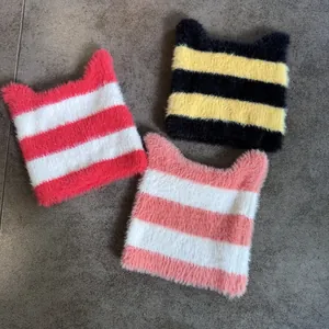 Lindos gorros de punto a rayas con orejas de gato en rojo, amarillo y rosa sobre gris