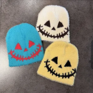 Close-up of three knitted Halloween hats with spooky faces in white, blue, and yellow