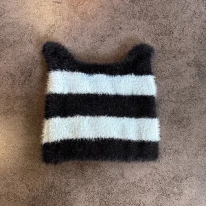 Detalle del gorro de punto con rayas y orejas de gato con textura suave y diseño tierno
