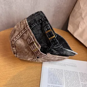 Berretto piatto vintage in denim lavato marrone e nero su tavolo in legno rustico
