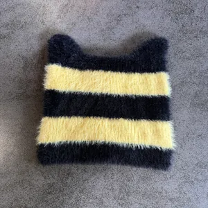 Primer plano del gorro de punto con orejas de gato, textura suave y rayas amarillas y negras